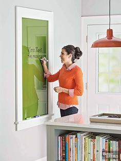 a woman is writing on the wall with a marker and an easel in front of her