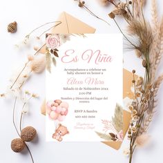 an elegant wedding card with flowers and leaves on the front is displayed next to some dried plants