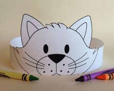 a paper cat hat with crayons next to it