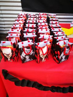 a table topped with lots of red and black paper bags filled with skully treats