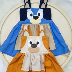 two children's aprons with animals on them are sitting on a white plate