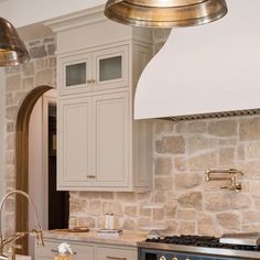 a kitchen with an oven, stove and sink in the middle of it is surrounded by stone walls