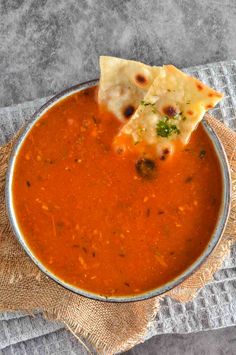 a metal bowl filled with soup and tortilla chips on top of a cloth