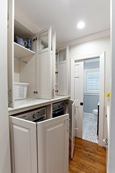 an empty kitchen with white cabinets and appliances in the center, including a washer and dryer