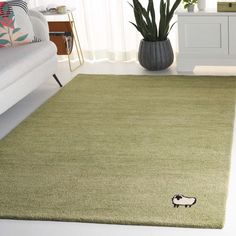 a green rug with a sheep on it in a living room next to a couch