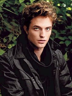 the young man is posing in front of some bushes and trees with his eyes wide open