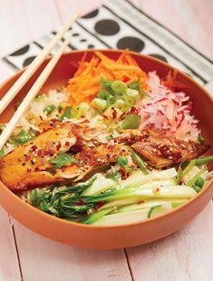 a bowl filled with meat and vegetables next to chopsticks