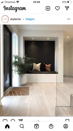 an empty living room with white walls and wood flooring on the side, along with a large planter filled with potted plants