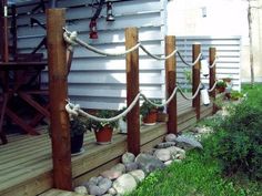 a wooden deck with some plants and rocks on the ground next to an outside building