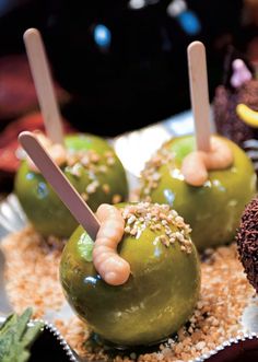 green apples with sticks sticking out of them on top of some sprinkles