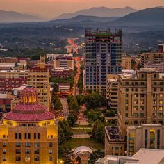 the city skyline is lit up at night with mountains in the background and buildings on both sides