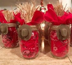 four mason jars with red and brown decorations in them