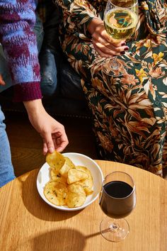 two people are sitting at a table with wine and food