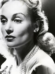 an old black and white photo of a woman with pearls on her head holding a ring