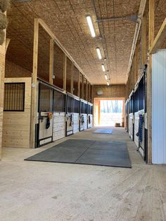 the inside of a horse barn with several stalls