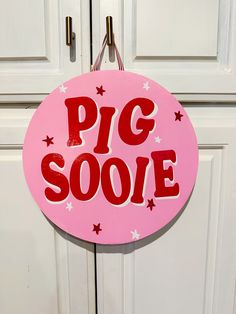 a pink sign that says pig sooe hanging from the side of a white door