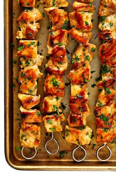 chicken kebabs on a baking sheet with tongs and garnishes