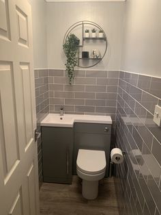 a small bathroom with grey tiles and white fixtures on the wall, toilet and sink