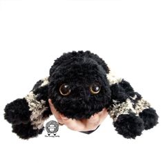 a black and white stuffed animal with big eyes on it's head, held up to the camera