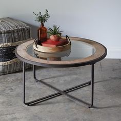 a small table with a glass top and metal frame around it, sitting next to a basket filled with fruit