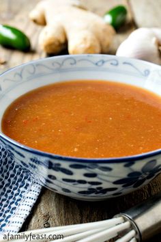 a blue and white bowl filled with soup on top of a wooden table next to garlic