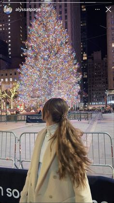 a woman standing in front of a large christmas tree