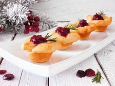 cranberry tarts on a white platter with berries and pine cones in the background