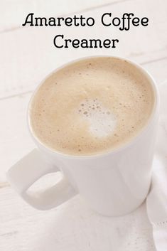 a cup of coffee with the words amarretto coffee creamer above it on a white wooden table