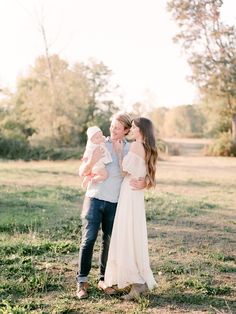 a man and woman are holding their baby girl in the middle of an open field