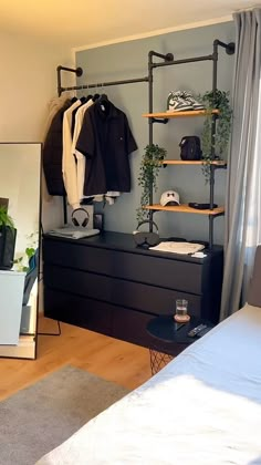 a bedroom with a bed, dresser and clothes rack in front of a mirror on the wall