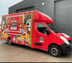 a red food truck parked in front of a building with an advertisement on the side