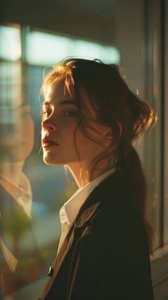 a woman standing in front of a window with her hair pulled back and looking off to the side