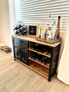 a wine rack with bottles and glasses on it in the corner of a room next to a window