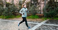 a woman running down the street with trees in the background