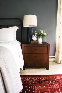 a bedroom with a bed, night stand and lamp on the nightstand next to it