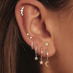 a woman's ear with five stars, moon and crescent piercings on it