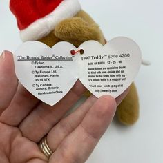 someone is holding two heart shaped tags in their left hand, with the label attached to them