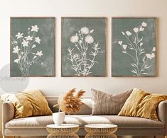 three paintings on the wall above a couch in a living room with wicker chairs