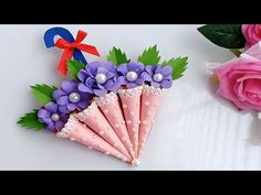 an arrangement of flowers and paper umbrellas on a white surface next to pink roses