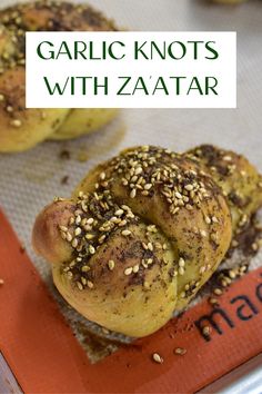 garlic knots with zaata are on a baking sheet and have sesame seeds sprinkled on them