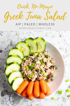 a white plate topped with cucumbers, carrots and tuna salad