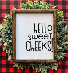 a sign that says hello sweet cheeks in front of a red and black checkered wall