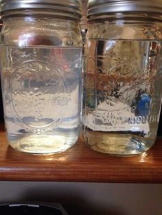 two mason jars sitting on top of a wooden shelf