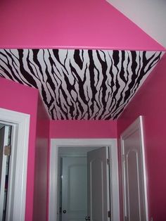 a bathroom with pink walls and zebra print on the ceiling