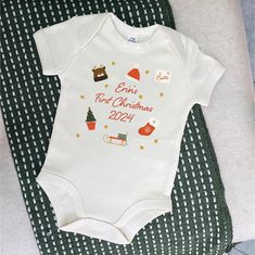 Personalised Baby's First Christmas Babygrow with name and 2024, featuring festive illustrations. Perfect gift for a new baby.  Celebrate your baby's first holiday season with our Personalised Baby's First Christmas Babygrow. Featuring your baby's name followed by "First Christmas 2024," this adorable babygrow is surrounded by festive illustrations, including a reindeer hat, Santa hat, letter to Santa, stocking, sledge, Christmas tree, and twinkling gold stars. Each charming design adds a magica Christmas Objects, Christmas Babygrow, Reindeer Hat, Alphabet Gifts, Letter To Santa, Personalized Ribbon, Santa Stocking, Baby Vest, Cotton Gifts