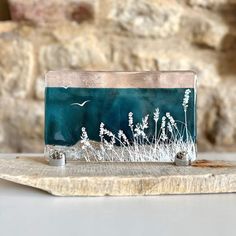 a green and white purse sitting on top of a wooden board next to a stone wall