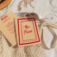 two menu cards sitting on top of a table next to a glass of watermelon