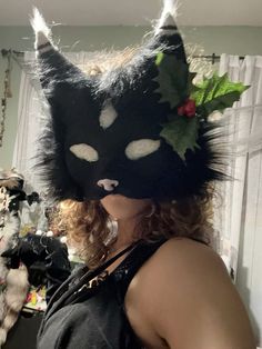 a woman wearing a black cat mask with flowers on her head