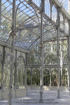 the inside of a building with glass walls and arches on each side, surrounded by trees