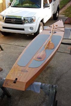 a surfboard sitting on top of a table next to a white truck